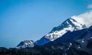 Majestatyczne szczyty Alp, pokryte śniegiem, z chmurami otulającymi wierzchołek. Widok na wejście na Mont Blanc.