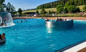 Słoneczny dzień na basenie w Czechach, blisko granicy. Ludzie kąpią się i relaksują w wodzie, ciesząc się wakacjami.