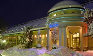 Zimowe atrakcje w Polanicy Zdrój: ośnieżony budynek z neonem "Pijalnia" i świątecznymi iluminacjami.