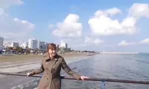 Kobieta na molo, w tle plaża i budynki. Piękny, słoneczny dzień na Cyprze w lutym.