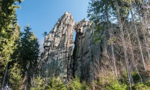 Skalny most rudawy, wyrzeźbiony przez naturę, góruje nad lasem.