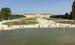 Wiedeń: Pałac Schönbrunn i jego ogrody, gdzie turyści spacerują pośród kwiatowych rabat i podziwiają architekturę.