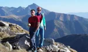 Para wędruje po skalistym szlaku, podziwiając majestatyczne **czerwone wierchy** w oddali.