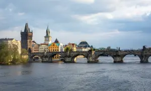 Most Karola w Pradze, kamienny, zabytkowy, z wieżami i rzeką Wełtawą.
