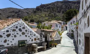 Urocza uliczka z białymi domami i kamiennymi detalami, idealna na gran canaria plan zwiedzania. W tle góry.