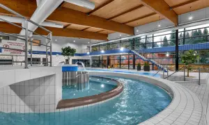 Wodny świat w aquaparku Špindlerův Mlýn: basen z wodospadem, jacuzzi i widokiem na las.