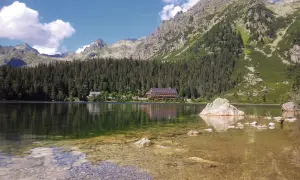 Malowniczy widok na Popradzki Staw. Trasa wokół jeziora prowadzi przez las, z widokiem na góry i hotel.