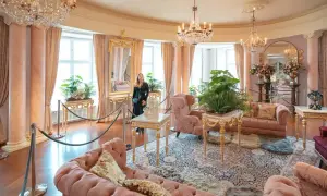 Eleganckie wnętrze, jak w zamkach hotelach w Polsce, z różowymi sofami, kryształowymi żyrandolami i bujną roślinnością.