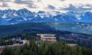Drewniana wieża widokowa w Zakopanem wznosi się pośród lasów, oferując zapierający dech w piersiach widok na ośnieżone Tatry.