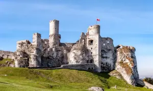 Ruiny zamku na skale, część Szlaku Orlich Gniazd, z polską flagą na wieży.