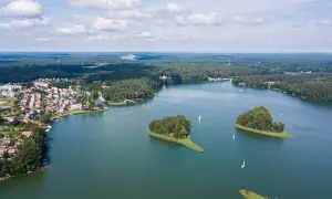 Malownicze jeziora w Polsce, z zielonymi wyspami i żaglówkami, otoczone lasami i domkami letniskowymi.