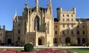 Piękny pałac w Lednicach z neogotycką architekturą i kwitnącymi rabatami kwiatowymi.