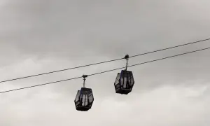 Dwie gondole kolejki **Gubalowka cable car** wiszą na linach na tle pochmurnego nieba.