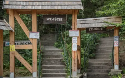 Kamienne schody prowadzą na trasę na Szczeliniec. Drewniane bramy z napisami "Wejście" i "Zeście" wyznaczają początek i koniec szlaku.