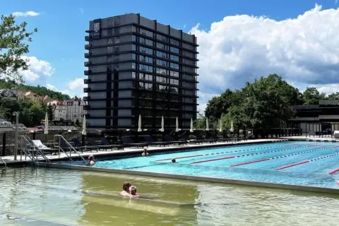 Relaks w karłowskich warach baseny termalne. Ludzie kąpią się w basenie z widokiem na nowoczesny hotel i malownicze miasteczko.