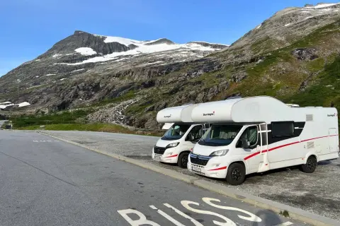 Dwa kampery zaparkowane na tle norweskich gór. Idealne na podróż kamperem w 2 tygodnie po Norwegii.