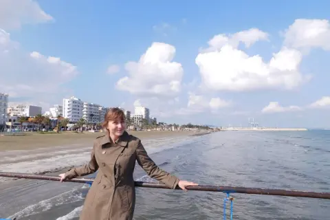 Kobieta na molo, w tle plaża i budynki. Piękny, słoneczny dzień na Cyprze w lutym.