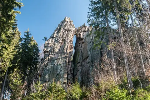 Skalny most rudawy, wyrzeźbiony przez naturę, góruje nad lasem.