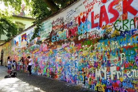 Kolorowa ściana Johna Lennona w Pradze, pokryta graffiti i cytatami, w tym "All You Need Is Love".