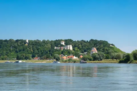 Widok na Wisłę i wzgórze z ruinami zamku, wieżą i kościołem. Kazimierz Dolny atrakcje zachwycają o każdej porze roku.