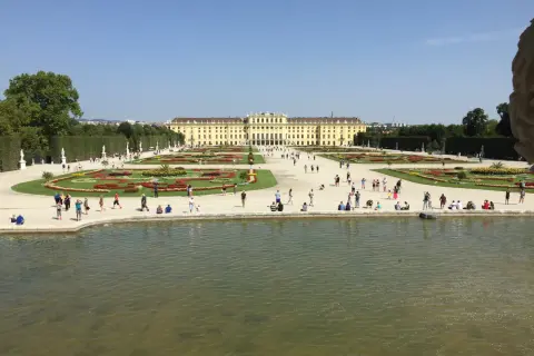 Wiedeń: Pałac Schönbrunn i jego ogrody, gdzie turyści spacerują pośród kwiatowych rabat i podziwiają architekturę.