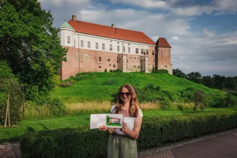 Kobieta trzyma szkic zamku, który przypomina miasto Ojca Mateusza.