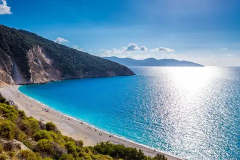 Widok na Myrtos, jedną z najpiękniejszych plaż w Grecji. Turkusowe morze, biały piasek i zielone wzgórza tworzą rajski krajobraz.