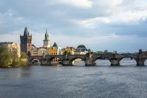 Most Karola w Pradze, kamienny, zabytkowy, z wieżami i rzeką Wełtawą.