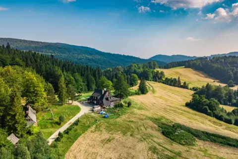 Malownicza bacówka nad Wierchomlą, gdzie trasa turystyczna prowadzi przez zielone wzgórza i lasy.