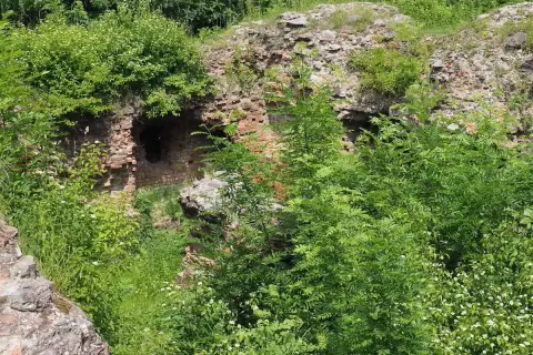 Ruiny na Górze Świętego Marcina, porośnięte bujną zielenią. Ceglane mury z otworami, jakby zapraszające do odkrycia tajemnic.