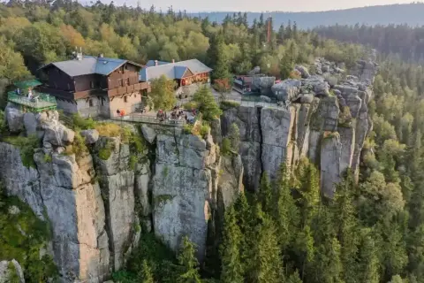 Góry Stołowe z górującymi nad lasem skalnymi formacjami i schroniskiem na szczycie.