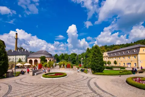 Słoneczny dzień w Kudowie Zdroju. Spacer po urokliwym parku, gdzie piękne budynki i zadbane rabaty kwiatowe tworzą niezapomniane **kudowa zdrój atrakcje**.
