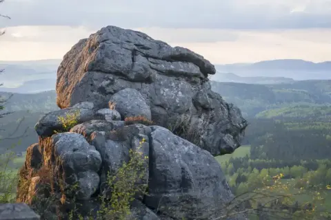 Gigantyczne formacje skalne, przypominające karłów, wznoszą się nad zieloną doliną. Błędne skały tworzą niezwykły krajobraz.