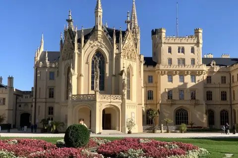 Piękny pałac w Lednicach z neogotycką architekturą i kwitnącymi rabatami kwiatowymi.