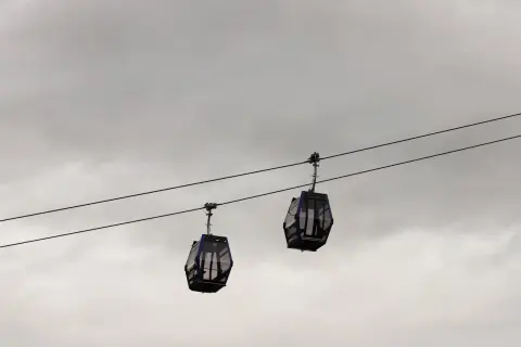 Dwie gondole kolejki **Gubalowka cable car** wiszą na linach na tle pochmurnego nieba.