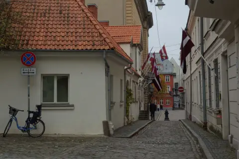 Urokliwa uliczka w Rydze, z łotewskimi flagami i brukowaną nawierzchnią. Idealne miejsce, by poczuć atmosferę miasta i odkryć, co zobaczyć.