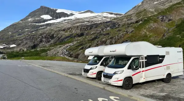 Dwa kampery zaparkowane na tle norweskich gór. Idealne na podróż kamperem w 2 tygodnie po Norwegii.