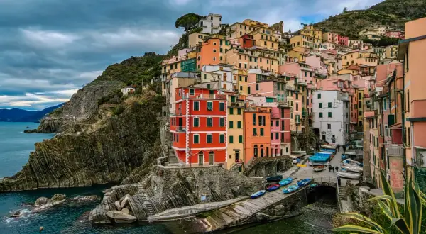 Kolorowe **miasta Cinque Terre** wznoszą się na skalistym wybrzeżu Ligurii. Domy przytulone do klifu, łodzie przy brzegu.