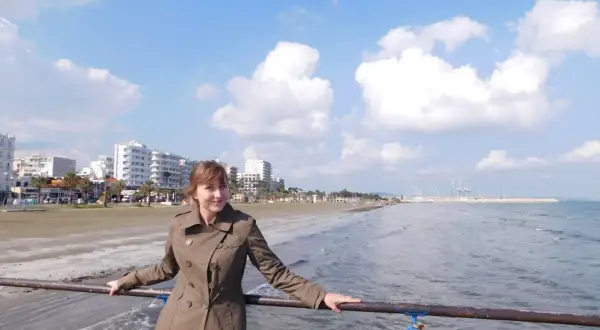 Kobieta na molo, w tle plaża i budynki. Piękny, słoneczny dzień na Cyprze w lutym.