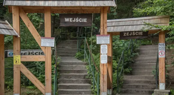 Kamienne schody prowadzą na trasę na Szczeliniec. Drewniane bramy z napisami "Wejście" i "Zeście" wyznaczają początek i koniec szlaku.