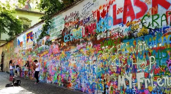 Kolorowa ściana Johna Lennona w Pradze, pokryta graffiti i cytatami, w tym "All You Need Is Love".