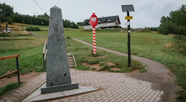 Pomnik na trójstyku Jaworzynka. Znaki graniczne i drogowskazy wskazują trasę.