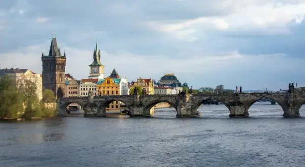 Most Karola w Pradze, kamienny, zabytkowy, z wieżami i rzeką Wełtawą.