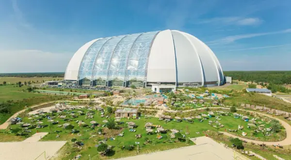 Krausnick tropical island: ogromna hala z basenami i leżakami na trawie, plaża do siatkówki, otoczona zielenią.