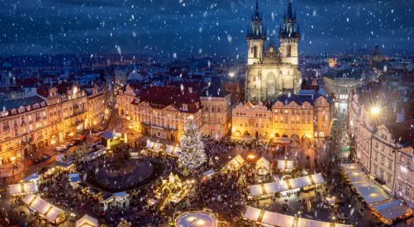 Tłoczny jarmark bożonarodzeniowy w Pradze, z oświetloną choinką i kościołem w tle, to jeden z najpiękniejszych jarmarków bożonarodzeniowych w Europie.