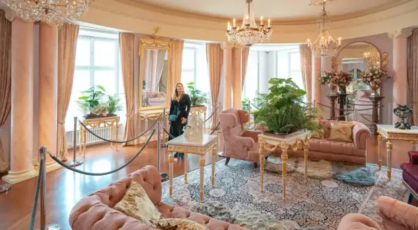 Eleganckie wnętrze, jak w zamkach hotelach w Polsce, z różowymi sofami, kryształowymi żyrandolami i bujną roślinnością.