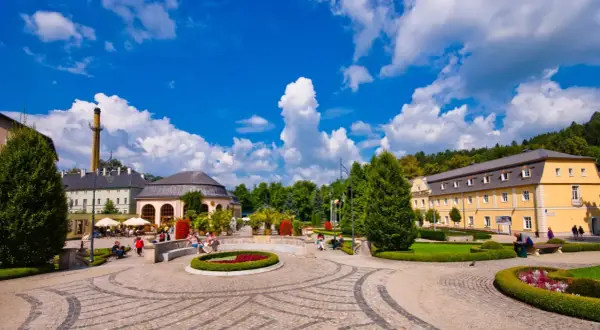 Słoneczny dzień w Kudowie Zdroju. Spacer po urokliwym parku, gdzie piękne budynki i zadbane rabaty kwiatowe tworzą niezapomniane **kudowa zdrój atrakcje**.