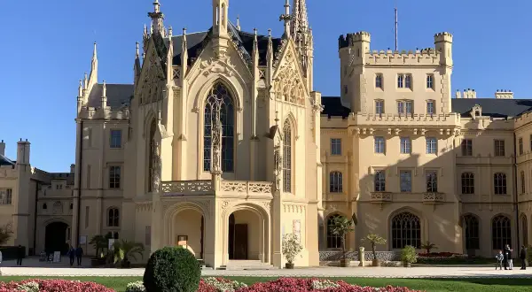 Piękny pałac w Lednicach z neogotycką architekturą i kwitnącymi rabatami kwiatowymi.
