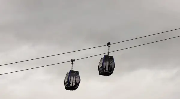 Dwie gondole kolejki **Gubalowka cable car** wiszą na linach na tle pochmurnego nieba.