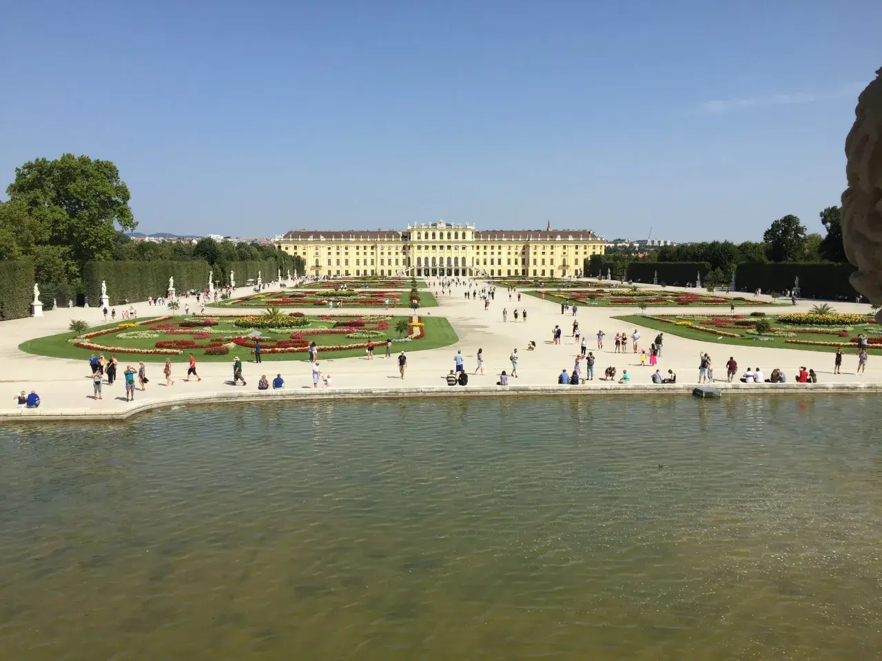 Wiedeń: Pałac Schönbrunn i jego ogrody, gdzie turyści spacerują pośród kwiatowych rabat i podziwiają architekturę.